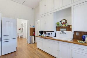 A kitchen with white cabinets, a refrigerator, a microwave, and a coffee maker.