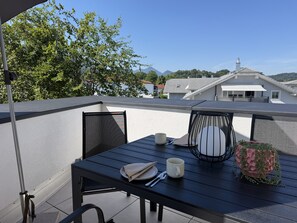A balcony with a table, chairs, and a potted plant. - Limone Apartment with Rooftop Terrace (Bernau am Chiemsee)
