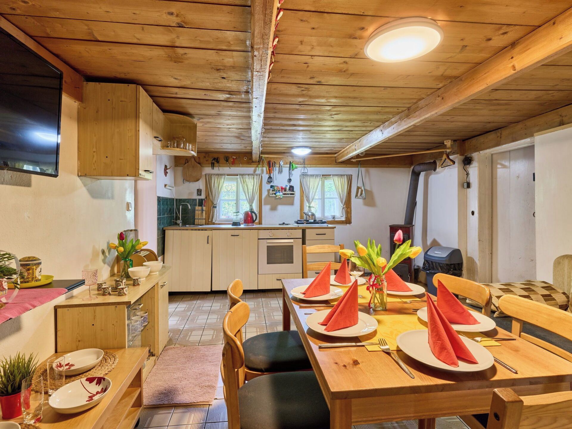 Interior acogedor de madera con comedor listo para cuatro, cocina con electrodomésticos modernos y una chimenea a la vista.