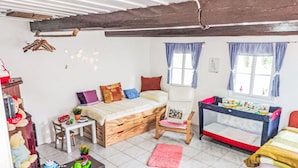 Un dormitorio infantil con cama, escritorio, silla, una mesita llena de juguetes y ventana con cortinas.