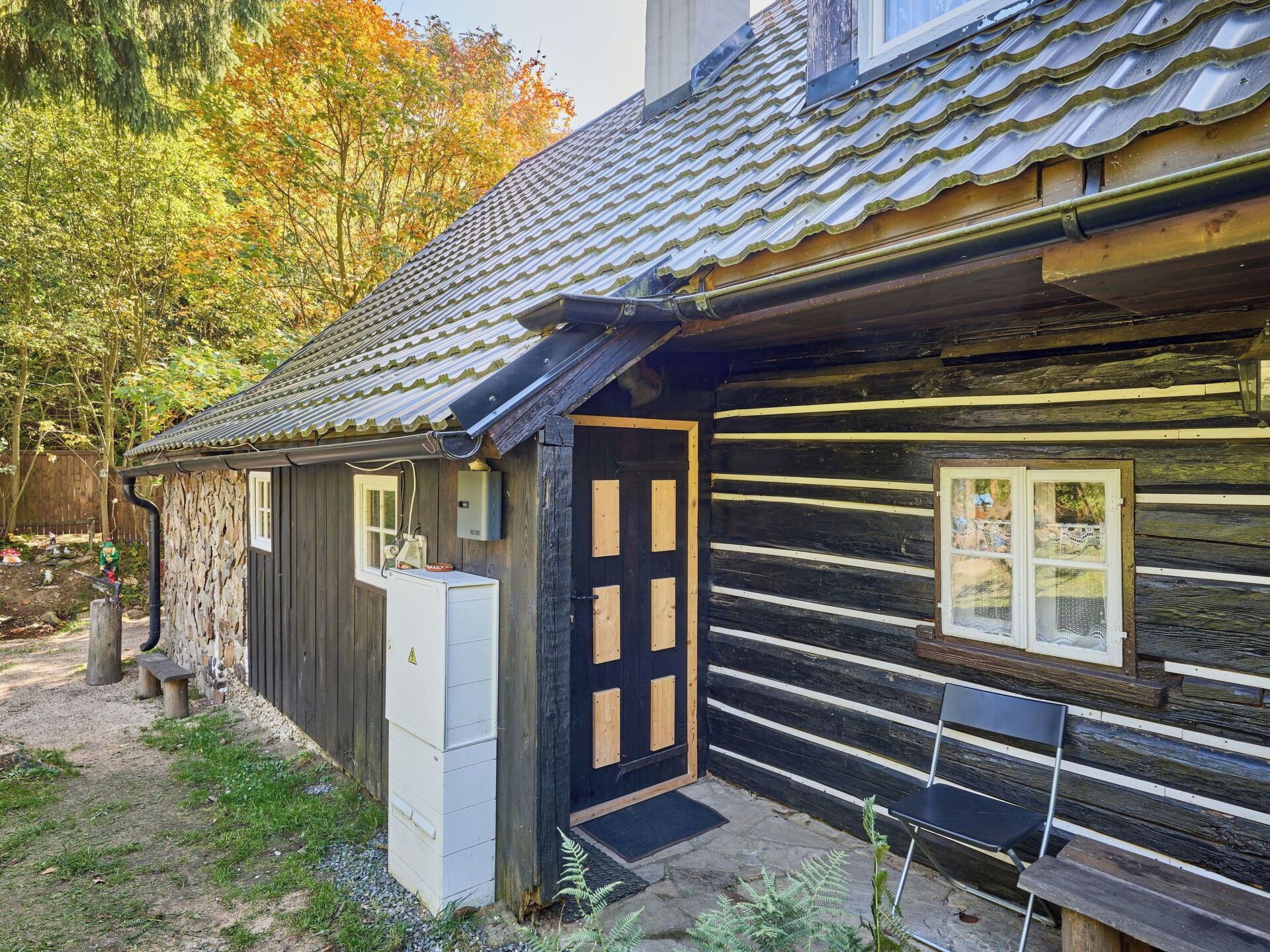 Une cabane rustique avec un toit en tuiles, une porte en bois et un banc à l’extérieur.