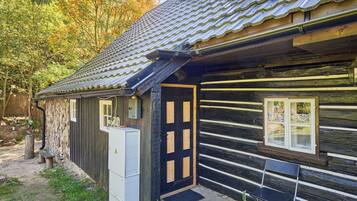 Une cabane rustique avec un toit en tuiles, une porte en bois et un banc à l’extérieur.
