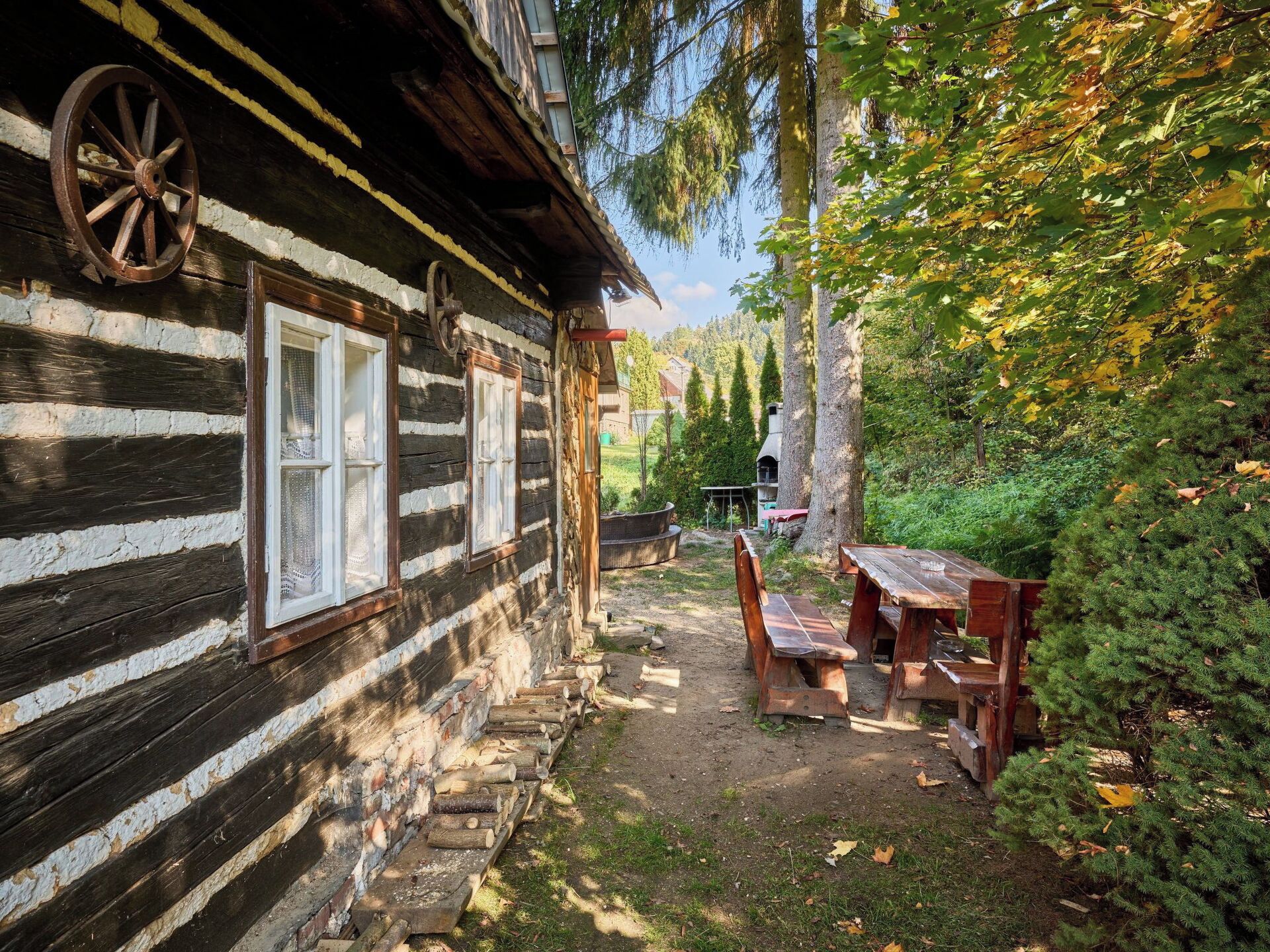 A rustic cabin with a wooden exterior, a wheel attached to the wall, and a picnic table set up outside.