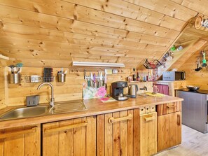 A wooden kitchen with a built-in sink, a coffee maker, and various kitchen utensils.