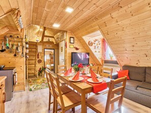 A cozy wooden interior with a dining area, kitchen, and a TV.