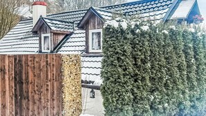 Una casa de madera tradicional con techo de tejas, valla de madera y paisaje cubierto de nieve.