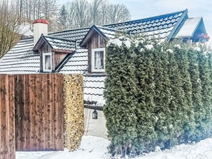 A traditional wooden house with a tiled roof, a wooden fence, and a snow-covered landscape.