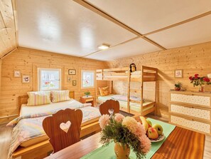 A cozy wooden cabin room with bunk beds, a wooden desk, and a dining table.