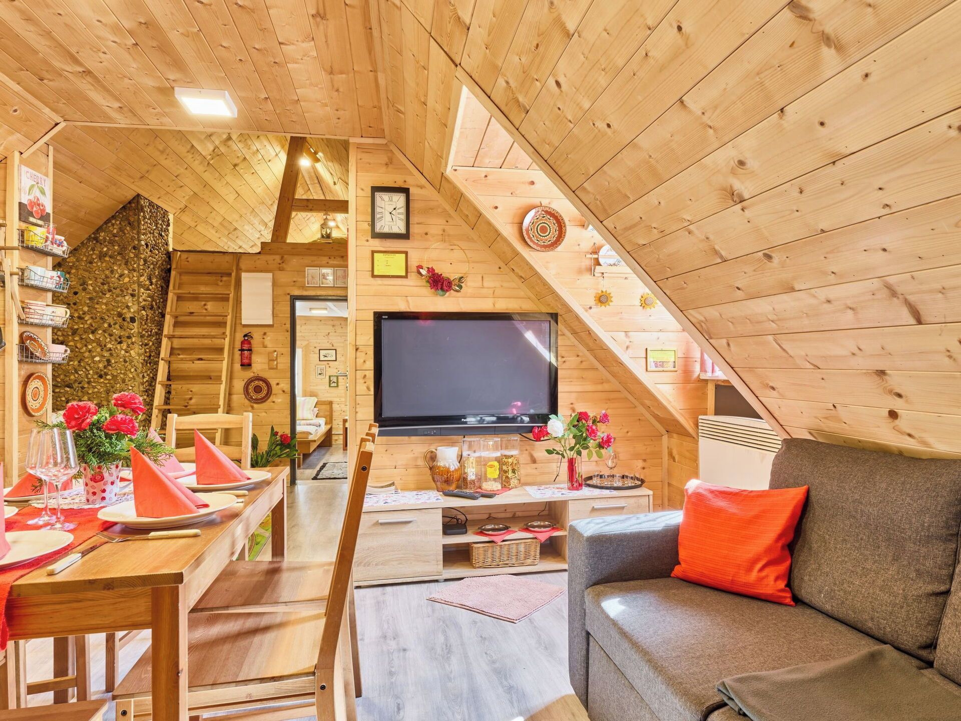 A cozy wooden interior with a dining area, a sofa, and a TV.