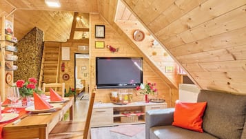 A cozy wooden interior with a dining area, a sofa, and a TV.