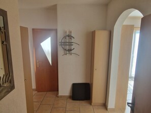 Ein Flur mit einer Holztür, einem schwarzen Gegenstand auf dem Boden und einem an der Wand befestigten Dekorationsstück.