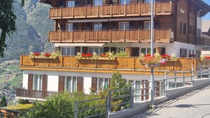 A multi-story wooden building with balconies, surrounded by mountains. - Birke, (Grächen), by Interhome (Grächen)