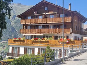 A multi-story wooden building with balconies, surrounded by mountains. - Birke, (Grächen), by Interhome (Grächen)