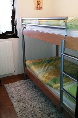 Una cama litera con estructura metálica y un colchón estampado en verde y amarillo.