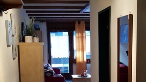 Een gang met een getextureerd vloerkleed, een houten kast en een klein krukje.