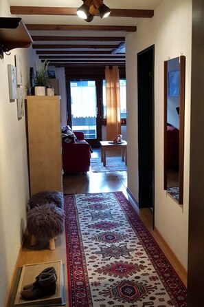 A hallway with a patterned rug, a wooden cabinet, and a small stool. - David 26D, (Grächen), 1623 by Interhome (Grächen)