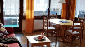 Een gezellige woonkamer met een eettafel, stoelen, een bank en een bijzettafeltje met een decoratief object.