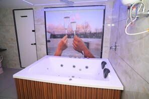 A modern bathroom with a large bathtub, a wooden vanity, and a glass shower enclosure.