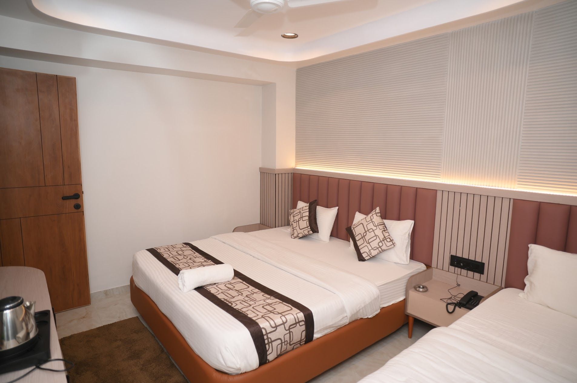 A hotel room with a large bed, bedside tables, a wardrobe, and a ceiling fan.