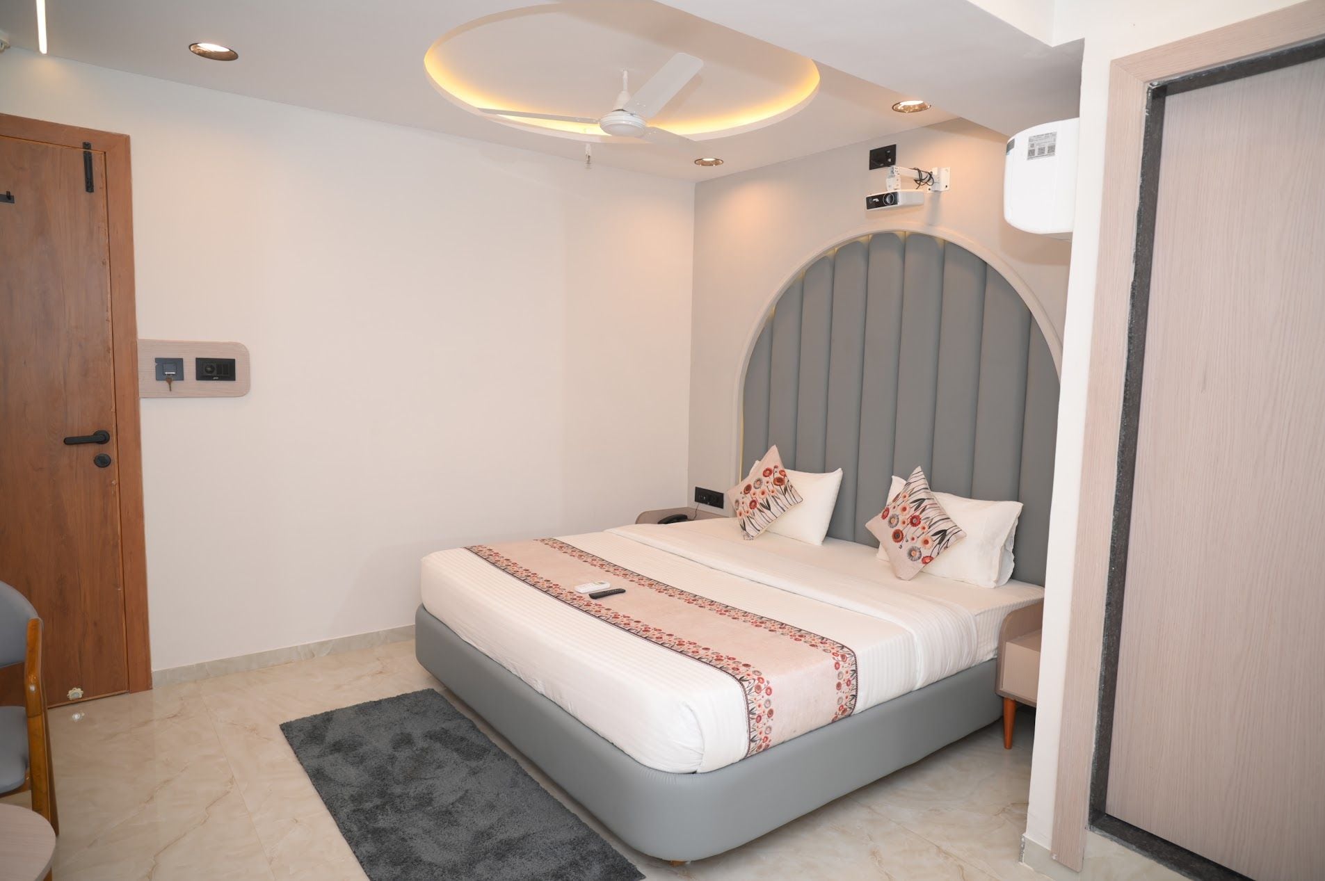 A modern bedroom with a bed, bedside tables, a ceiling fan, and a door.