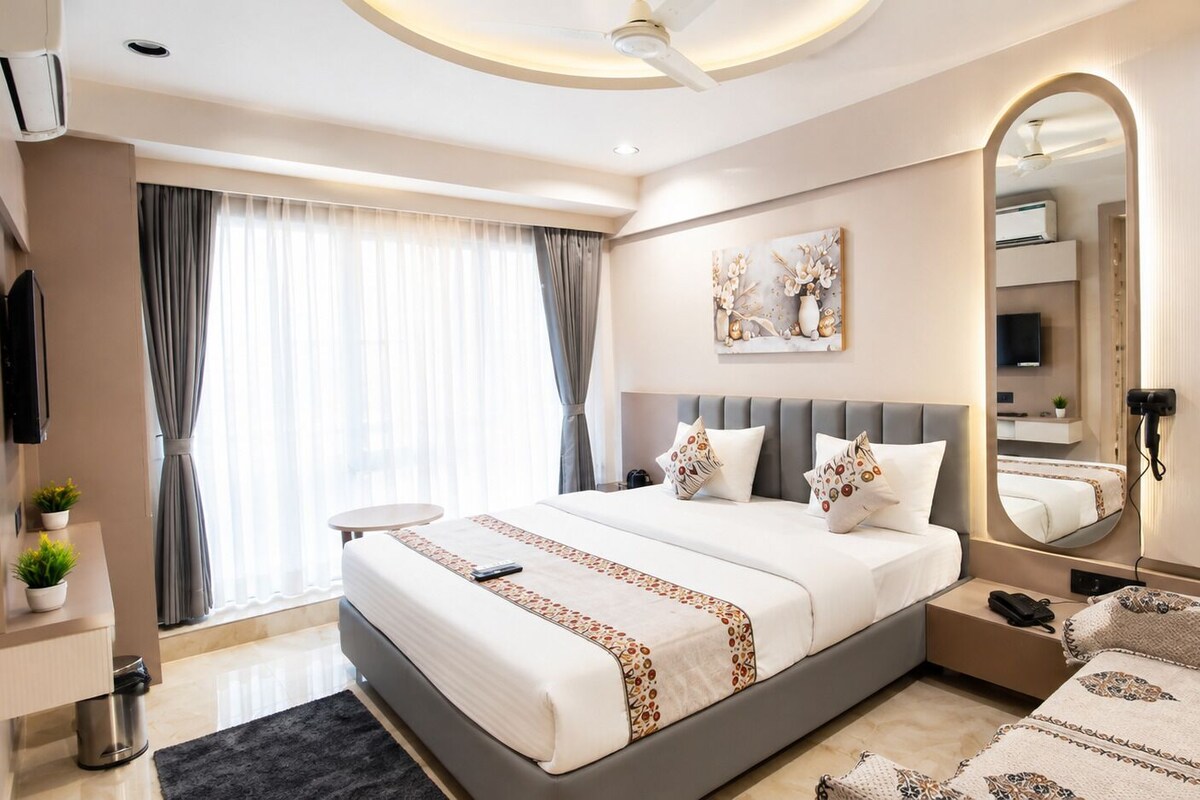 Habitación de hotel moderna con una cama grande, mesitas de noche, un espejo y vistas a la ciudad.