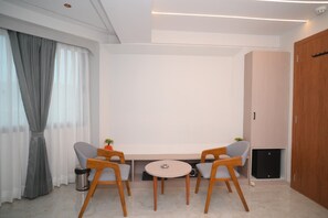 Una habitación moderna con una mesa redonda, dos sillas, una planta pequeña y un altavoz.