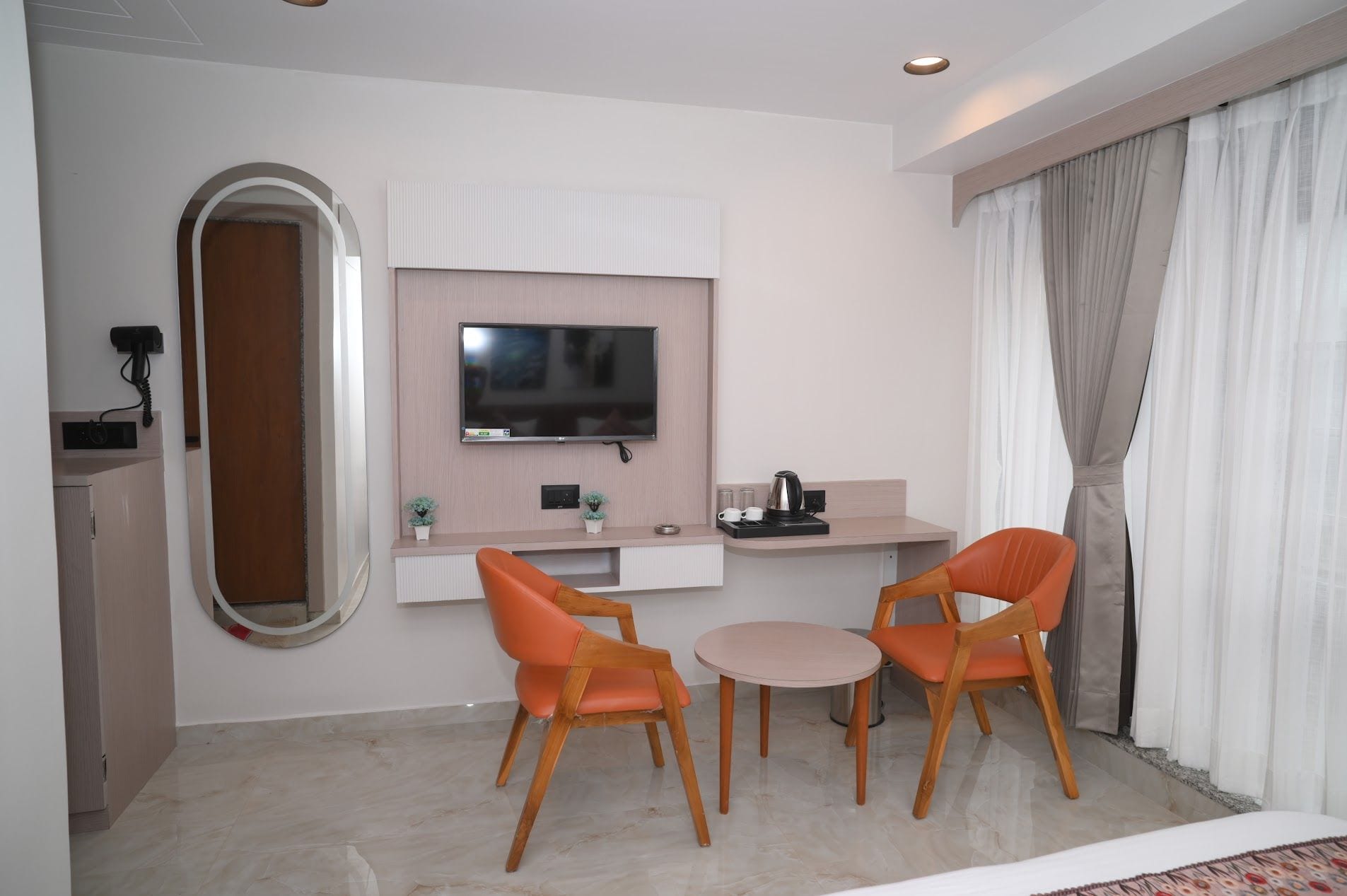 Ein Hotelzimmer mit Fernseher, einem kleinen Tisch, zwei Stühlen, einer Kaffeemaschine und einem Spiegel.