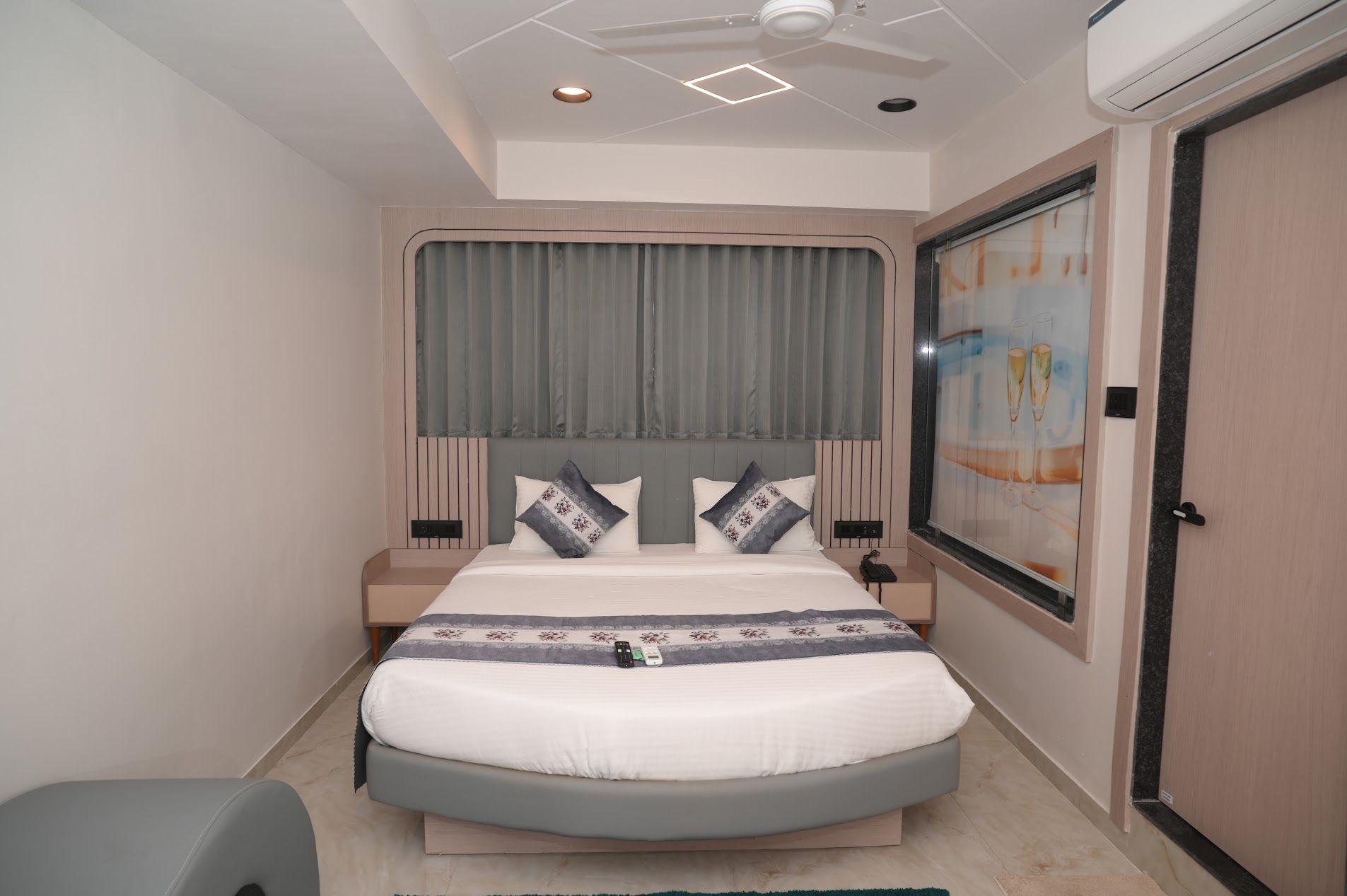 Ein modernes Schlafzimmer mit einem Bett, Nachttischen, einem Deckenventilator und einem Fenster mit Vorhängen.