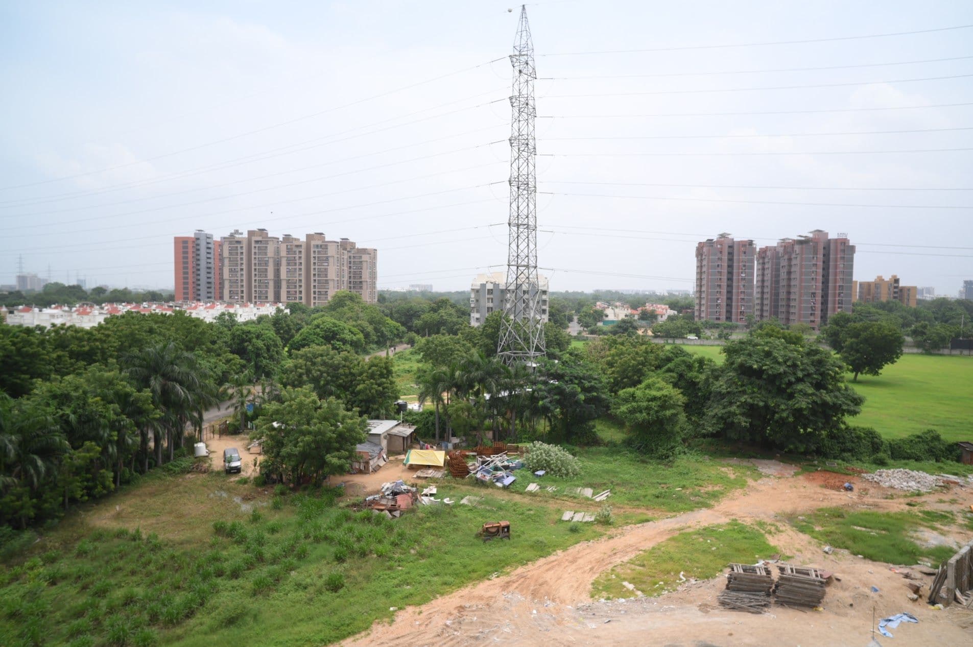 Zona residencial con edificios altos, una torre de transmisión eléctrica y zonas verdes dispersas.