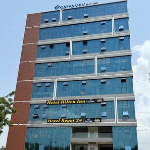 A multi-story hotel building with 'Hotel Hilton Inn' and 'Hotel Regal 24' signage.