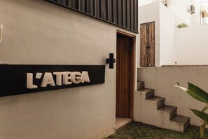 Entrada de un edificio con un cartel que dice 'L'ATEGA' y una puerta de madera.