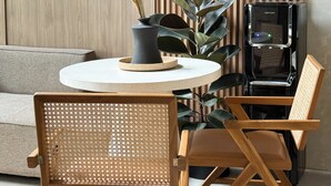 Una sala de estar moderna con una mesa redonda, dos sillas de madera, un sofá y una decoración con plantas.