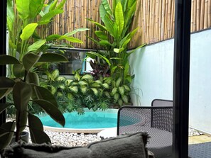 A room with a view of a swimming pool, surrounded by various plants and a bamboo wall. - Private Jungle Pool Loft Near Canggu Beach • Guest Favorite • Fast WiFi (Canggu)