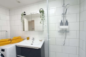 A modern bathroom with a glass shower enclosure, a white sink, and a mirror above it. - La Green par Your Sweet Loc (Compiègne)
