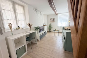 A modern living room with a wooden ceiling beam, a dining area with a table and chairs, and a seating area with a sofa. - La Green par Your Sweet Loc (Compiègne)