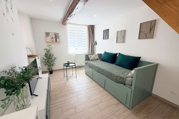 A modern living room with a green sofa, a small table, and a potted plant.
