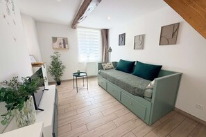 A modern living room with a green sofa, a small table, and a potted plant. - La Green par Your Sweet Loc (Compiègne)