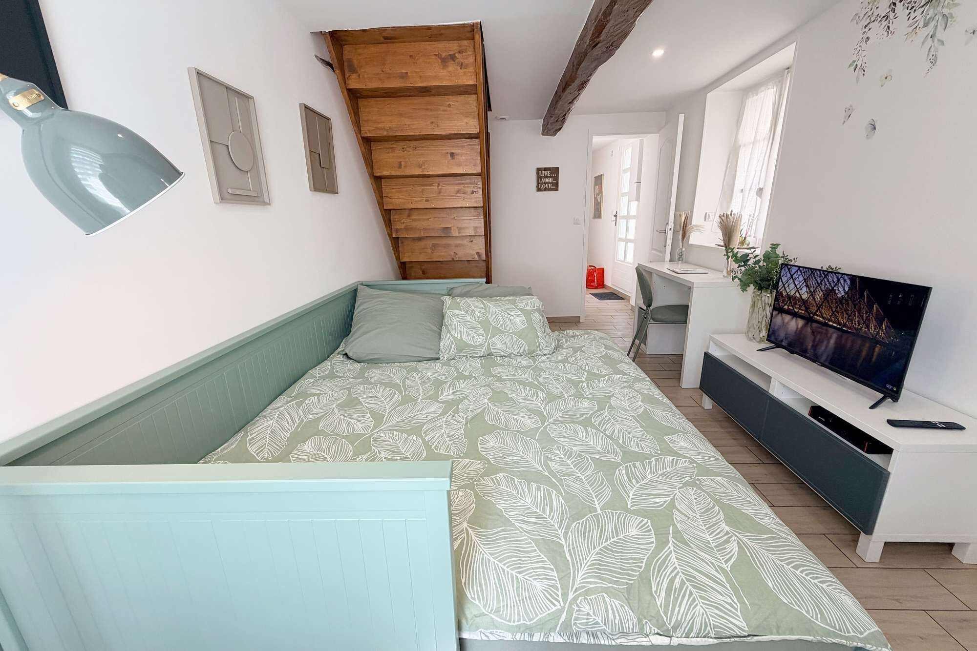 A room with a bed, a desk, a television, and a window.