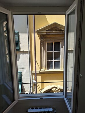 Ein Zimmer mit großem Fenster, Blick auf ein Gebäude mit Balkon und einer Tür.