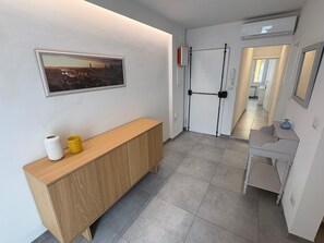 Ein Flur mit einem Holzkonsolentisch, einem Stadtbild im Bilderrahmen und einer weißen Tür mit schwarzem Griff.