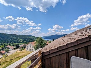 A wooden building with a sloped roof overlooking a valley with houses and a lake. - Le Martin Pêcheur: Between Nature and Downtown. (Gérardmer)