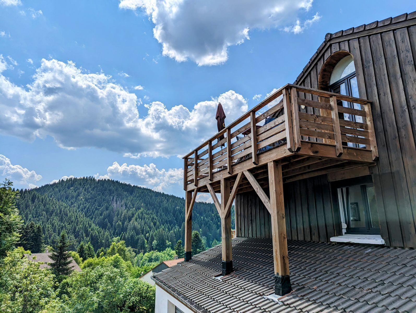 Ein Holzbalkon mit Blick auf eine bewaldete Bergkette.
