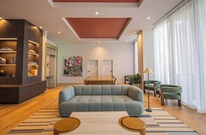 A modern living room with a sectional sofa, a dining table, and a bookshelf. - The Crosby Balcony Studio Miami Worldcenter (Miami)