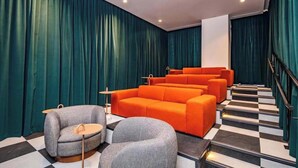 Eine Hotellobby mit Schachbrettfußboden, einer Treppe und einer Sitzecke mit orange- und grauen Möbeln.