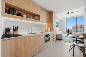 A modern kitchen with wooden cabinetry, a built-in oven, and a large window offering a city view. - The Crosby Balcony Studio Miami Worldcenter (Miami)
