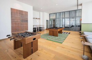 A modern indoor space with a foosball table, a pool table, and a seating area with a sofa and chairs. - The Crosby Balcony Studio Miami Worldcenter (Miami)