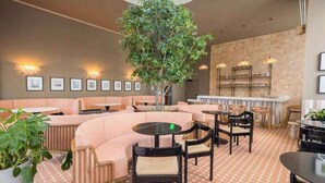 Ein modernes Interieur mit Sitzbereichen, einem zentralen Baum und Wandleuchten.