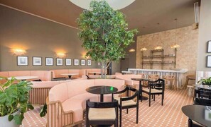 A modern interior with seating areas, a central tree, and wall-mounted lighting. - The Crosby Balcony Studio Miami Worldcenter (Miami)