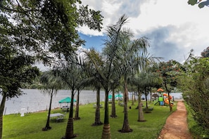A lakeside park with picnic tables, a playground, and a path leading to the water.