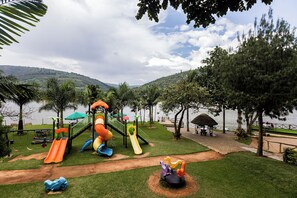 A playground with slides and swings, a picnic area, and a view of a lake and hills. - The Green Resort (55VH+7R6, Kigali,)